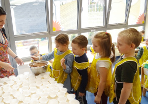 11 dzieci kolejno nalewają masę do papilotek